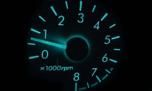 Close-up view of a speedometer dial displaying RPM readings with a glowing blue background.